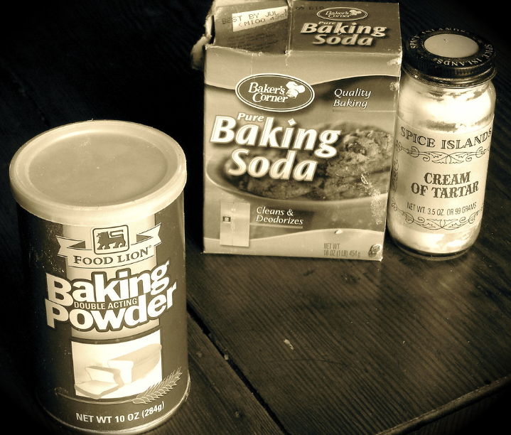 a box of baking soda, a can of baking powder, and a bottle of tartar cream on a table