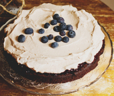 A cake with whipped cream abnd blueberries on a glass plate