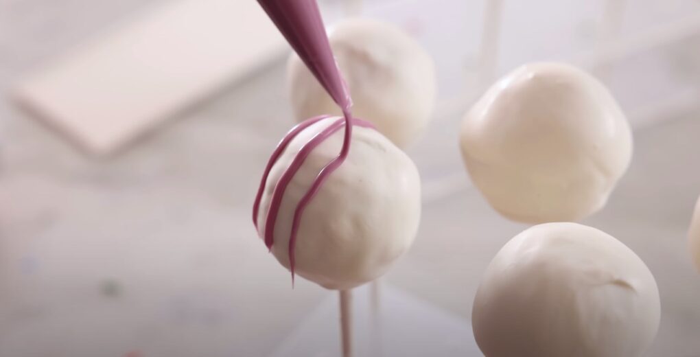 white rounded cakes on sticks with lavender candy melt swiping